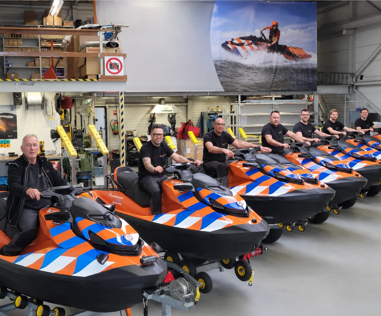 Reddingsbrigade Nederland technicians beside a line of rescue watercraft in the IJmuiden workshop